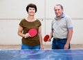 Portrait of elderly couple with rackets for table tennis