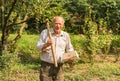 Portrait of elderly man with ax on his shoulder and a half of wood in his hand