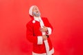 Portrait of elderly man with gray beard wearing santa claus costume holding hands on belly and can`t stop laughing hard, hearing