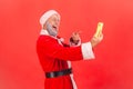 Portrait of elderly man with gray beard wearing santa claus costume standing with smart phone Royalty Free Stock Photo