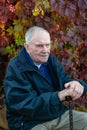 Portrait of an elderly man in his garden. Old gray-haired man with a cane, resting sitting on a bench against the background of Royalty Free Stock Photo