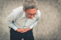 Portrait of elderly man holding his hands on aching stomach