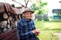 Portrait of elderly man sitting on bench outdoors in garden, resting and looking at camera. Royalty Free Stock Photo