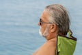 Portrait of an elderly man sitting in a tourist chair against the backdrop of the sea.  Concept: tourism and travel, outdoor recre Royalty Free Stock Photo