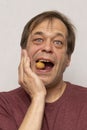 Portrait of an elderly man 45-50 years old cracking a walnut on a light background strong teeth, dental care. Healthcare, dental c Royalty Free Stock Photo