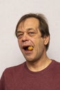 Portrait of an elderly man 45-50 years old cracking a walnut on a light background strong teeth, dental care. Healthcare, dental c Royalty Free Stock Photo