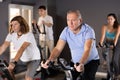 Portrait of mature man taking indoor cycling class at fitness center, doing cardio riding bike Royalty Free Stock Photo