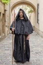 Portrait of an elderly monk 45-50 years old with a beard and a black cassock, walking down the street with a staff against the bac Royalty Free Stock Photo