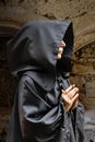 Portrait of an elderly nun 60-65 years old in black cassock on a stone wall. Concept: pilgrimage to holy places,