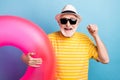 Portrait of elderly retired cheerful man holding rubber ring having fun resort isolated over bright blue color
