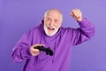 Portrait of elderly retired trendy pensioner cheerful man playing game rejoice isolated over bright violet purple color Royalty Free Stock Photo