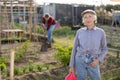 Portrait of an elderly satisfied woman with watering can for watering plants in garden Royalty Free Stock Photo