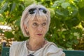 Portrait of an elderly thoughtful woman 60-65 years old on a blurred background of a green city park.