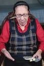 Portrait of an elderly woman with a beautiful wrinkled face in glasses holds pills in her hands to choose medicine. The