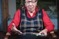 Portrait of an elderly woman with a beautiful wrinkled face in glasses holds pills in her hands to choose medicine. The