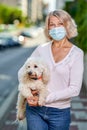 Portrait elderly woman with a dog outdoors an antivirus mask Royalty Free Stock Photo