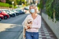 Portrait elderly woman with a dog outdoors an antivirus mask Royalty Free Stock Photo