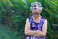 Portrait of an elderly woman hair curlers and looking down while standing in a garden Royalty Free Stock Photo