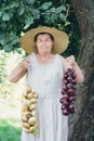 Portrait of an elderly woman in a hat holding a onions