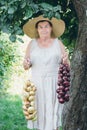 Portrait of an elderly woman in a hat holding a onions