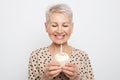 Portrait of elderly woman holding birthday cupcake celebrating anniversary. Royalty Free Stock Photo