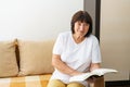 Portrait of an elderly woman reading book on couch at home. Caucasian pensioner Royalty Free Stock Photo