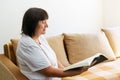 Portrait of an elderly woman reading book on couch at home. Caucasian pensioner Royalty Free Stock Photo
