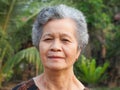 Portrait of an elderly woman with short gray hair, smiling and looking at the camera while standing outdoors. Space for text. Royalty Free Stock Photo