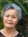 Portrait of an elderly woman smiling and looking at camera while standing in a garden Royalty Free Stock Photo