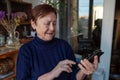 Portrait of an elderly woman using a smartphone. Elderly woman near window at home using mobile phone Royalty Free Stock Photo