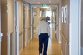 Portrait of elderly woman walking down hallway in retirement home background