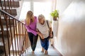 Caregiver helping senior woman climb staircase Royalty Free Stock Photo