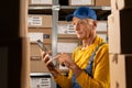 Portrait of elderly worker checking inventory using tablet computer. Old man working in a warehouse with rows of shelves Royalty Free Stock Photo