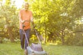 Portrait of eldery senior man working in the summer garden walking on a grass field