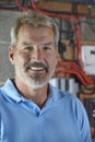 Portrait Of Electrician Standing Next To Fuseboard