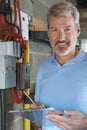 Portrait Of Electrician Standing Next To Fuseboard