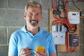 Portrait Of Electrician Standing Next To Fuseboard