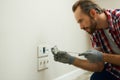 Portrait of electrician wearing protective gloves, using a screwdriver while installing new plug socket in a house Royalty Free Stock Photo