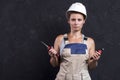 Portrait of electrician woman in uniform and white helmet holds in hand wire-cutters and nippers. Female worker in workwear