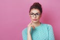 Portrait of elegance thoughtful woman having hair bun in bright skirt isolated on pink background touching chin and have a great i