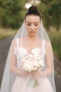 Portrait of elegand bride with bouquet. Young bride outdoors