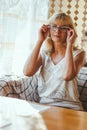 Portrait of elegant attractive blonde Caucasian an aged woman with stylish hair and glasses in white t-shirt sitting at a dining Royalty Free Stock Photo