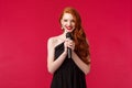 Portrait of elegant beautiful young woman with red long hair wearing evening dress, holding microphone, performer Royalty Free Stock Photo