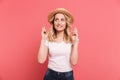 Portrait of elegant blond woman 20s wearing straw hat keeping fingers crossed and wishing for luck Royalty Free Stock Photo