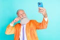 Portrait of elegant charismatic granddad hold telephone take selfie hand touch mustache isolated on teal color