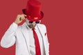 Portrait of handsome gentleman in white suit, red top hat and glasses on copy space background Royalty Free Stock Photo