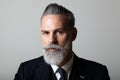 Portrait of elegant middle aged bearded gentleman wearing trendy suit over empty gray background. Studio shot, business