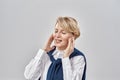 Portrait of elegant middle aged caucasian woman wearing business attire, adjusting her earbuds, smiling with eyes closed Royalty Free Stock Photo