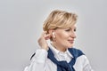 Portrait of elegant middle aged caucasian woman wearing business attire and earbuds adjusting her hair, smiling aside Royalty Free Stock Photo