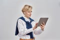 Portrait of elegant middle aged caucasian woman wearing business attire and earphones holding, using tablet pc while